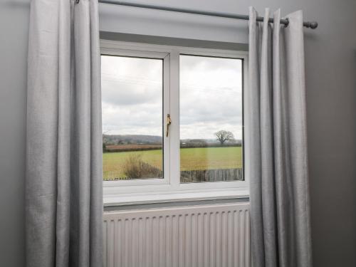a window with curtains and a view of a field at 26 Tansey in Shepton Mallet