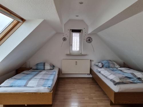 two beds in a attic room with a window at Fewo-O3-4-6-Personen-23km-bis-Frankfurt-Nord in Ober-Mörlen