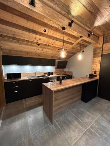 a large kitchen with wooden ceilings and a counter at Chalet Jean (Coeur de Morzine) Jacuzzi & Sauna in Morzine