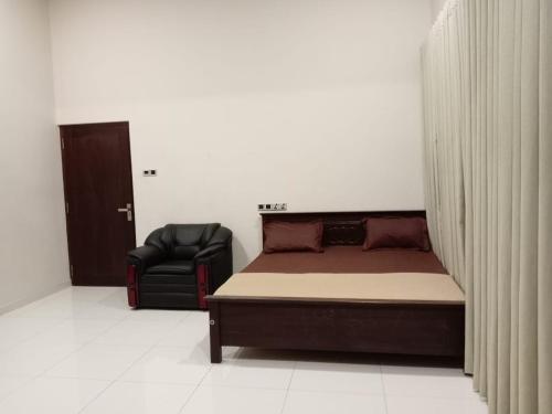 a bedroom with a bed and a black chair at Thalangama Lakeview Lodge in Battaramulla
