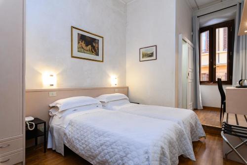 a white bedroom with a bed with white sheets at Hotel Julia in Rome
