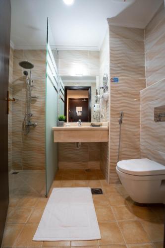 a bathroom with a toilet and a sink and a shower at فندق مزايا in Az Zāhir