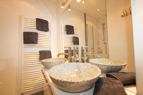 Baño con 3 lavabos frente a un espejo en Haus Herz, en Haus im Ennstal