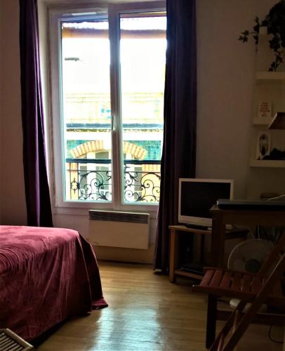 - une chambre avec une grande fenêtre et un balcon dans l'établissement appartement Paris bohème, à Paris