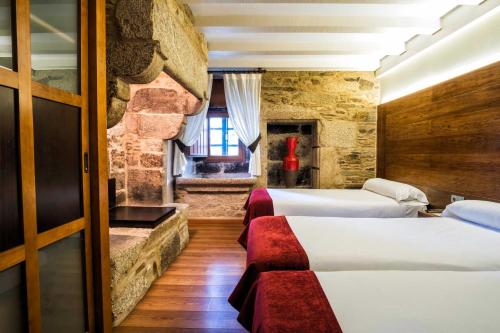 a hotel room with three beds and a window at Hotel Alda Bonaval in Santiago de Compostela