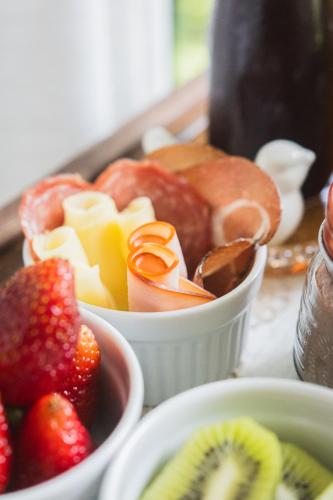 a tray of food with strawberries and fruit in bowls at Locanda Montecielo Pousada Boutique - Vale dos Vinhedos in Bento Gonçalves