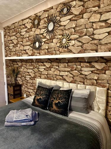a stone wall behind a bed with pillows on it at "Tranquil Village Hideaway Bungalow"near Kings Lynn in King's Lynn