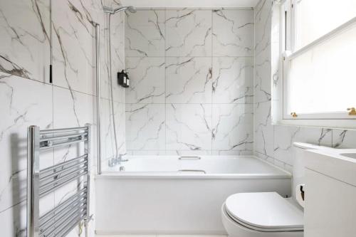 a white bathroom with a tub and a toilet at Contemporary central flat in Clerkenwell Green in London