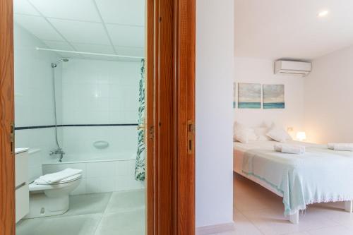 a bedroom with a bed and a bathroom with a shower at Apartamentos Es Dolç in Colònia de Sant Jordi