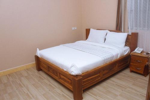 ein Schlafzimmer mit einem Holzbett und einem Telefon darauf in der Unterkunft Briston Hotel - Mugumu in Mugumu