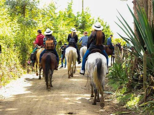 a group of people riding horses down a dirt road at Casa Pandora A 5 minutos aeropuerto Medellin in Santa Elena