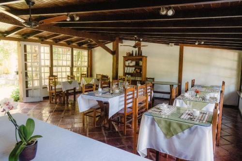 a dining room with white tables and chairs and windows at Pousada Serra da Bocaina Paraty in Paraty