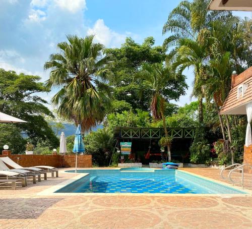 una piscina en un complejo con palmeras en Hermosa casa de campo con piscina y zonas de juego, en Villeta