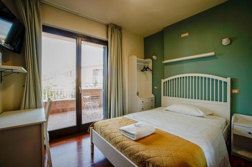 a bedroom with a bed with green walls and a window at SIGIS HOTEL Fiumicino in Fiumicino