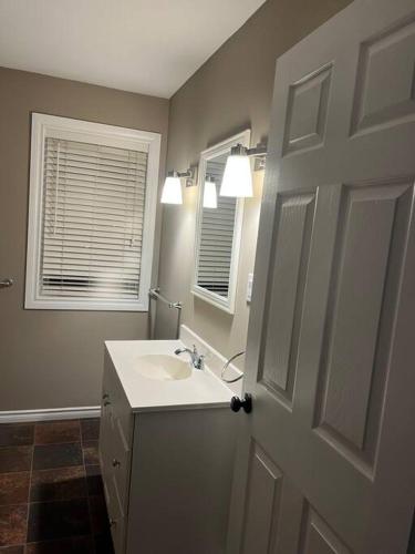 a bathroom with a sink and a mirror and a door at Blue door loft upper apartment in Thorold