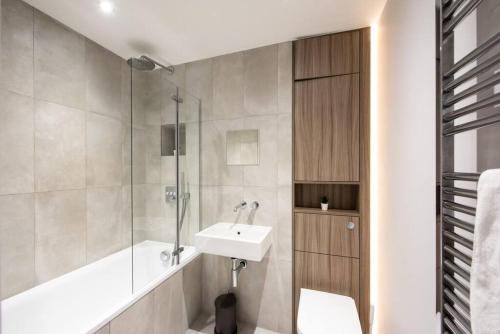 La salle de bains est pourvue d'un lavabo, d'une baignoire et d'une douche. dans l'établissement Space Apartments - Central Brentwood Apartment - Secure Parking - Fast Wifi - Flat 8, à Brentwood