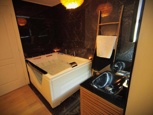 une salle de bain avec un lavabo et une baignoire dans l'établissement Love room avec jaccuzzi, à Mormant