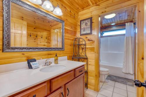 a bathroom with a sink and a toilet and a mirror at Bear Cove by AvantStay Hot Tub Pool Table in Pigeon Forge