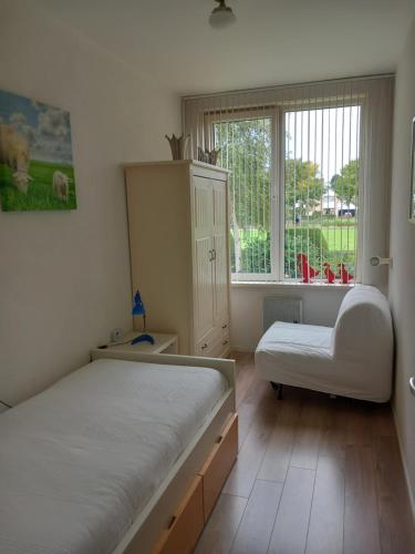 a bedroom with two beds and a chair and a window at Appartement AanZee in Hoek van Holland