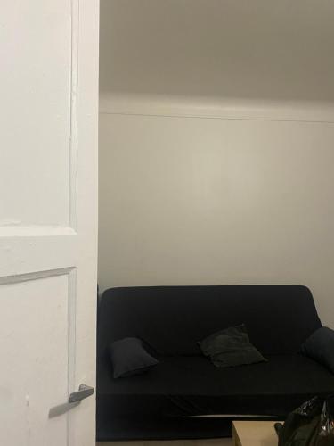 - un canapé noir dans une chambre dotée d'un mur blanc dans l'établissement Grand studio 30M2 Asnières sur Seine Centre-Ville, à Asnières-sur-Seine