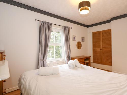 een slaapkamer met een bed met witte lakens en een raam bij 5 Melinda Cottages in West Runton