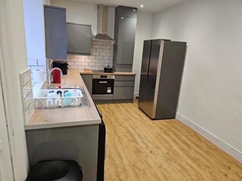 uma cozinha com electrodomésticos em aço inoxidável e pisos em madeira em Stylish & Quiet Space em Manchester