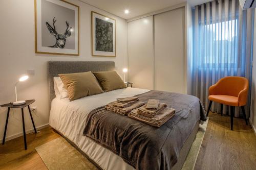 a bedroom with a bed and a orange chair at Casa do Barbeiro - View of the River Minho in Melgaço