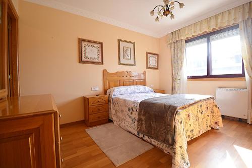 - une chambre avec un lit, une commode et une fenêtre dans l'établissement Apartamento As Carolinas, à Vilagarcía de Arousa