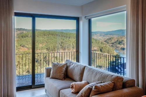 a living room with a couch and large windows at Casa do Barbeiro - View of the River Minho in Melgaço