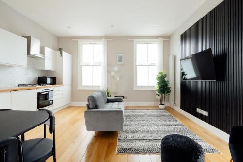 uma sala de estar com um sofá e uma televisão de ecrã plano em Contemporary & Chic 1 Bedroom Apartment in Honor Oak em Londres