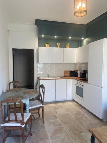 a kitchen with white cabinets and a table and chairs at Bel appartement de 40m² à louer in Nice