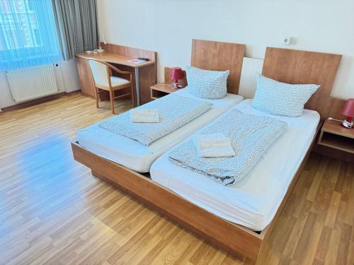 two beds in a room with a table and a chair at Pension Sonnenschein in Halle an der Saale