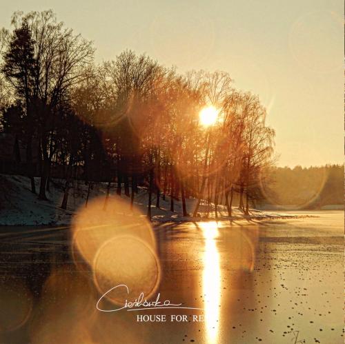 a sunset over a frozen lake with the sun shining at Cieślówka in Leżajsk