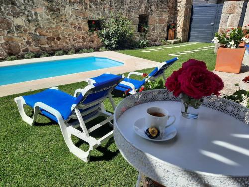 uma mesa com uma chávena de café e cadeiras ao lado de uma piscina em Casa do Abade - Country House em Viseu