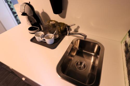 een aanrecht met een wastafel en kopjes erop bij Naomi app,Netflix,between bus and train station in Zagreb