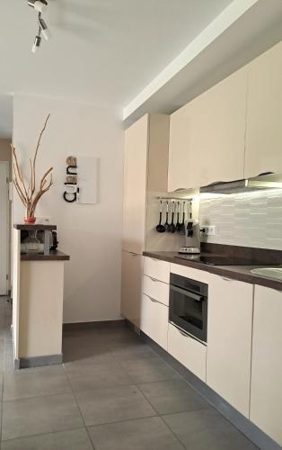 a kitchen with white cabinets and a stove at Superbe T3, havre de paix, entre plage et village in Capbreton