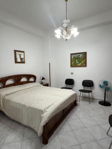 una camera da letto con letto, sedie e lampadario a braccio di Da Maria a Terrasini