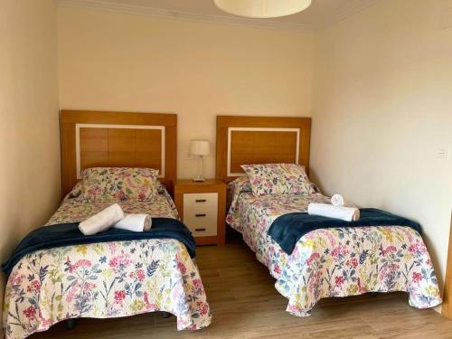 een slaapkamer met 2 bedden en een tafel met een lamp bij Apartamentos Melgarden - Campo del Marqués in Santoña