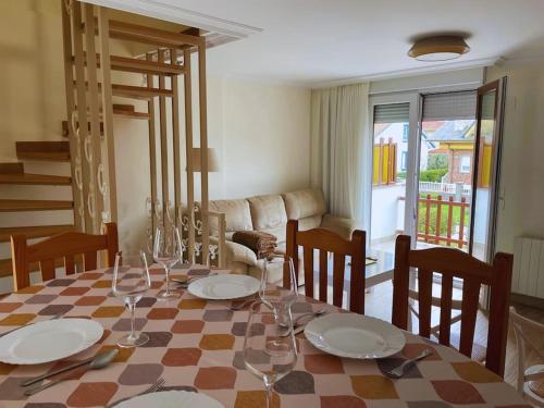 una sala da pranzo con tavolo, piatti e bicchieri da vino di Apartamentos Melgarden - Campo del Marqués a Santoña