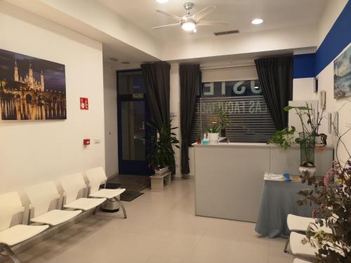 a waiting room with white chairs and a counter at Hostel de las Facultades in Santander