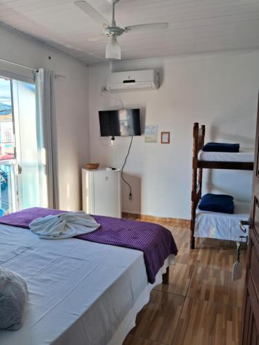 een slaapkamer met een bed met paarse lakens en een raam bij Pousada Caminho do Mar in Paraty
