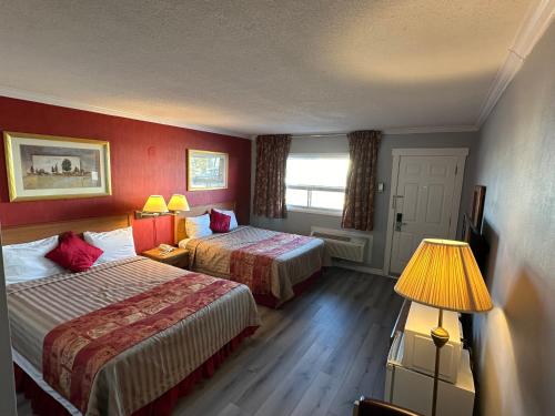 a hotel room with two beds and a window at HOTEL CLASSIC COMFORT in Cornwall