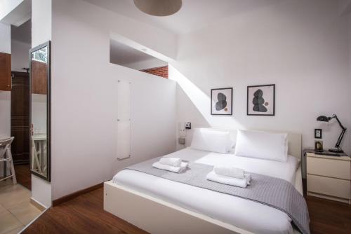 City Cave Apartment في مدينة هيراكيلون: غرفة نوم بيضاء بسرير ابيض ودرج
