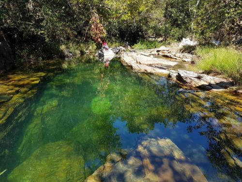 a river with green water and rocks and trees at Pousada Fazenda Vitoria in São João Batista do Glória