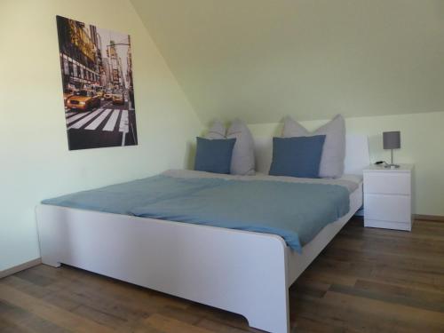ein weißes Bett mit blauen Kissen im Schlafzimmer in der Unterkunft Wohlfühloase by Rent Rooms Rietz in Stein bei Nürnberg