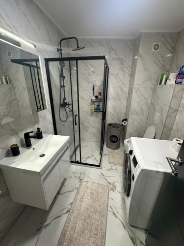 een witte badkamer met een douche en een wastafel bij APARTMAN DBR -Dobrinja Sarajevo in Sarajevo