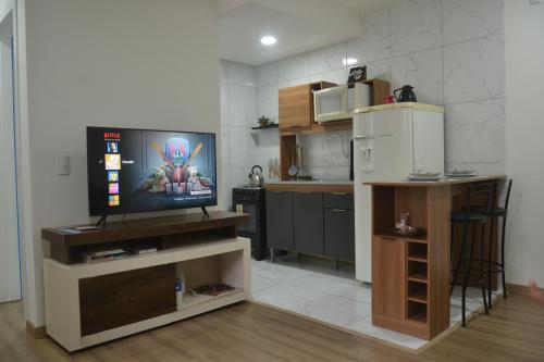 a living room with a television and a kitchen at Refúgio em Pelotas Com NF-E in Pelotas