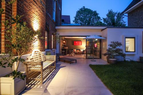 a patio with two benches and an umbrella at Stunning, architecturally designed Garden Studio with Parking in London