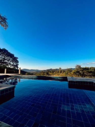 una gran piscina con un cielo azul en el fondo en Estância Vista dos Pireneus en Pirenópolis