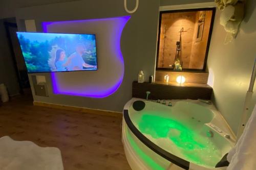 a bathroom with a tub with a tv on the wall at جاكوزي وغرفة سينما شقه فاخرة في ممشى الهجرة VIP in Al Madinah
